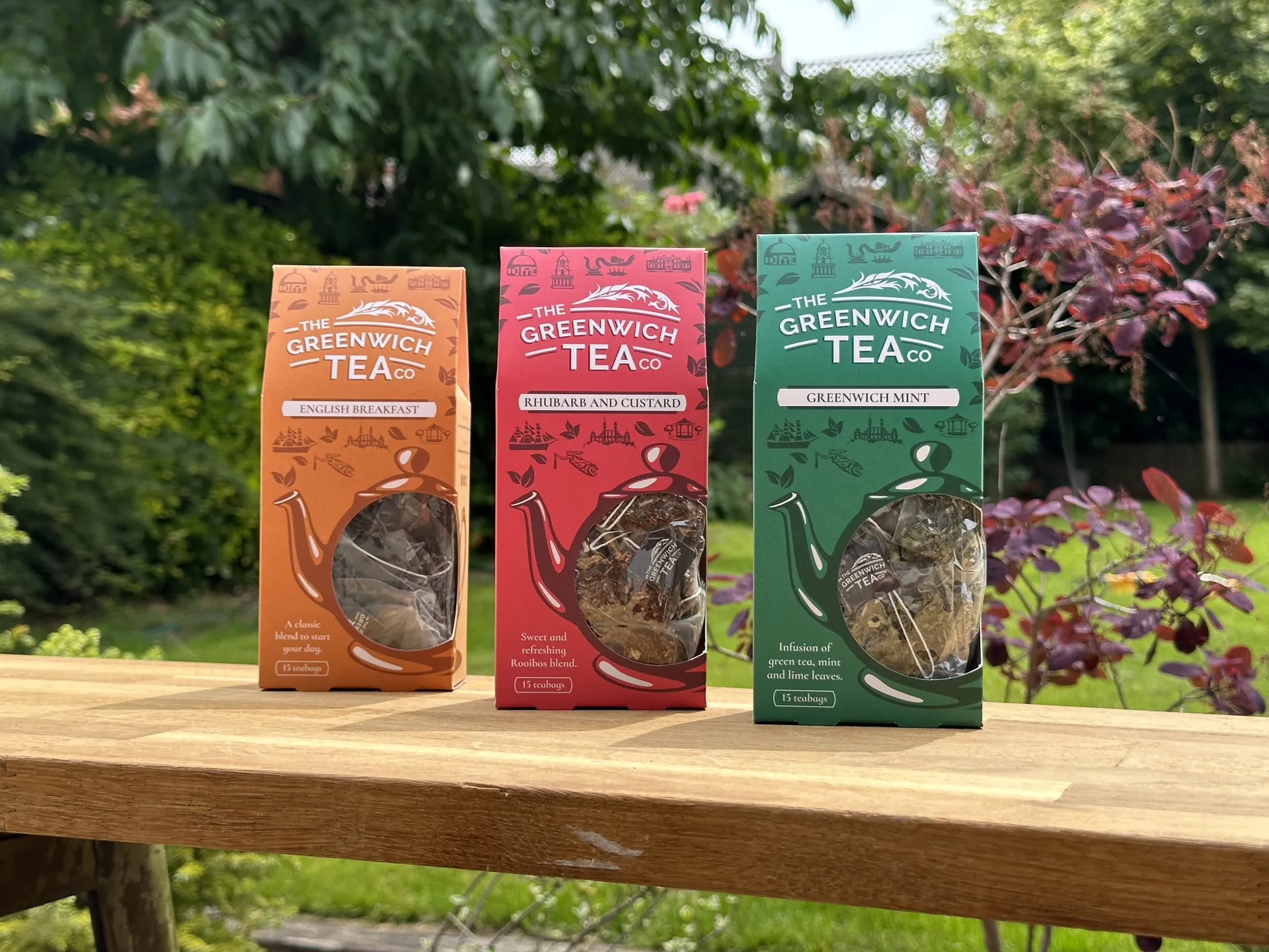 Greenwich Tea Company tea packs in orange, pink and green on a garden table